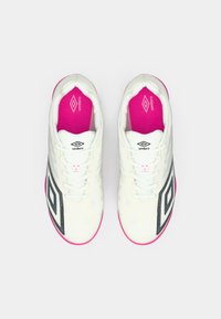 Pari valkoisia Umbro-urheilukenkiä mustalla logolla sivuilla, valkoisilla nauhoilla ja kirkkaan vaaleanpunaisilla sisäpohjilla yksinkertaisella valkoisella taustalla.