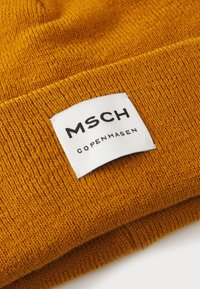 Mustard yellow knit beanie with a white label. The label displays "MSCH" in bold black letters and "COPENHAGEN" below in smaller text.