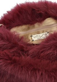 Maroon faux fur handbag interior with beige lining; features a zippered pocket and a label. Soft, textured material enhances tactile appeal.