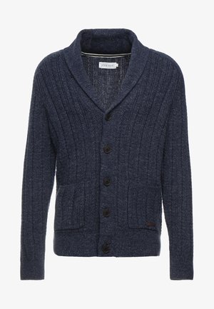 Navy blue knit cardigan with ribbed texture, shawl collar, front buttons, and two patch pockets. Features a small leather tag detail.