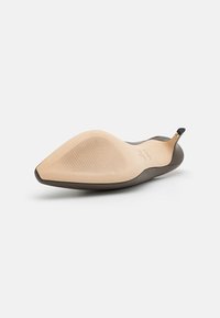 Pointed toe flat shoe with a smooth brown exterior and a beige rubber sole. Features subtle texture and a small black accent at the heel.
