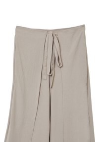 Pantaloni beige a gamba larga realizzati in tessuto morbido, con vita regolabile e una silhouette fluida con spacchi laterali per maggiore movimento.