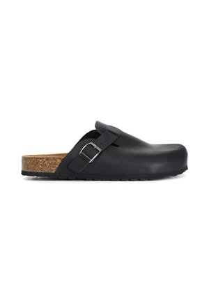 Black slip-on clog with adjustable strap and metal buckle, contoured cork footbed, and black rubber sole, side view on white background.