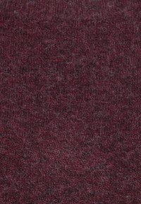 Burgundifärgad textil med en mjuk, fluffig yta, som har en tät väv och subtila variationer i färgintensitet.