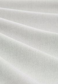 Tissu textile blanc avec un tissage fin et texturé, montrant de douces plis et des variations subtiles de lumière. Convient à diverses applications.