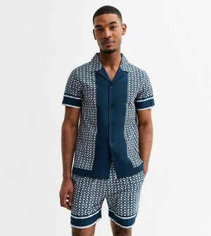 Set coordinato di camicia a maniche corte e pantaloni corti di colore blu scuro con un motivo geometrico bianco. Tessuto leggero, chiusura con bottoni frontale e dettagli a contrasto.
