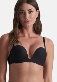 Reggiseno nero a scollo profondo con tessuto morbido, coppe modellate e spalline regolabili. Presenta un design profondo a V nella parte anteriore, ideale per abbigliamenti scollati.
