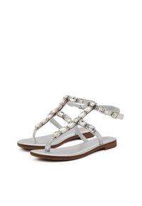 Sandali piatti argento con design a T-strap, impreziositi da gemme ovali trasparenti, dotati di una morbida soletta e suola in legno.