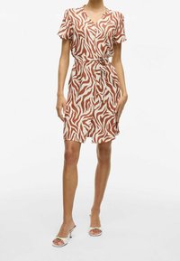 Brun och vit zebra-mönstrad kort klänning med V-ringning och bälte i midjan, tillverkad av lätt tyg, med korta ärmar och en luftig form.