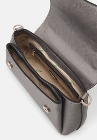 Grå syntetisk crossbody-taske med struktureret yderside, topklaff, guldhardware og et indre med flere rum og logo-print foring.