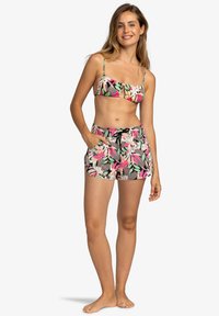 Maillot de bain deux pièces à motifs floraux avec un haut de bikini à volants et un short taille haute. Motif tropical coloré avec des bretelles ajustables et un cordon de serrage.