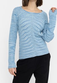 Blå ribbad långärmad topp med ett texturerat mönster, vid halsringning och åtsittande manschetter, tillverkad av mjukt, lätt material.