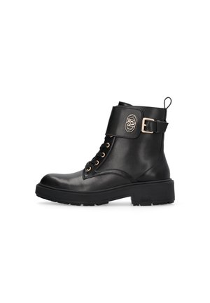 Black leather ankle boots with a thick sole, gold hardware accents, lace-up front, and a side buckle detail. Features a pull tab on the heel.