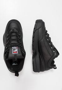 Mustat urheilukengät, joissa on sileä nahka päällinen ja tekstuuriset yksityiskohdat. Ominaisuuksiin kuuluvat nauhat, pehmustettu kaulus ja kumipohja.