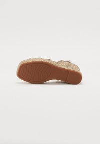 Sandale compensée avec une plateforme en jute tissé, des brides en cuir beige et une semelle en caoutchouc avec un motif texturé pour une meilleure adhérence.
