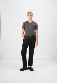 Gray cotton t-shirt paired with black corduroy pants. The pants feature an elastic waistband and side pockets. Black, chunky-soled shoes.