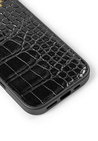 Funda de teléfono negra con patrón de cocodrilo y acabado brillante, con recortes para puertos y botones, enmarcada en plástico negro mate.