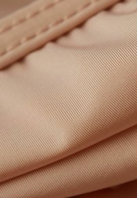 Beige, tekstureret stof med fine, parallelle linjer. Blød overflade, der viser glat drapering og subtil glans. Detaljeret syning synlig langs kanten.