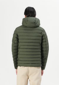 Padded jacket in olive green with a detachable hood. Horizontal quilted pattern, smooth texture, and elastic cuffs.
