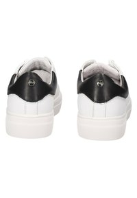 Sneaker bianchi con tallone in pelle nera, suola in gomma e dettagli testurizzati. Presentano un piccolo logo esagonale sul retro.