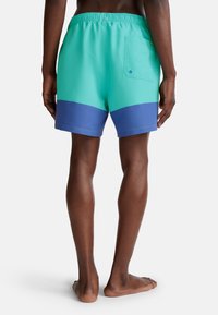 Zwemshorts in mintgroen met een navy blue ondergedeelte, voorzien van een elastische tailleband en een achterzak met knoopsluiting.