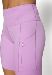 Lila höga leggings med en mjuk, stretchy tyg och sidofickor med dragkedja. Har en subtil, reflekterande logotyp på midjan.