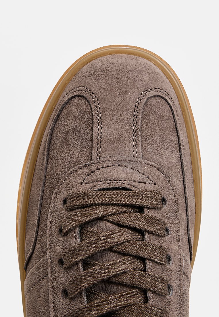 Sneaker mit einem Obermaterial aus Wildleder in einem gedeckten Braunton, runder Spitze, kontrastierender brauner Schnürung und Gummisohle mit strukturiertem Finish.