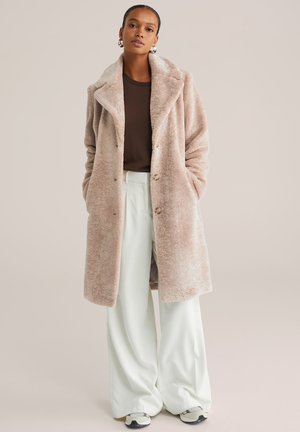 Faux fur frakke i lys pink med bred krave, forreste knapper og sidelommer, parret med løse, ribbede bukser i mintgrøn.