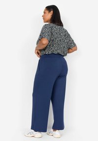 Námornícky nohavice v širokom strihu z mäkkého materiálu, doplnené kvetinovým topom s krátkymi rukávmi a voľným strihom. Outfit dopĺňajú tenisky.