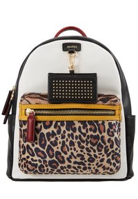 Mochila blanca y negra con un bolsillo frontal de estampado de leopardo, cremallera amarilla, tirador de cremallera rojo y etiqueta de llavero negra con tachuelas.