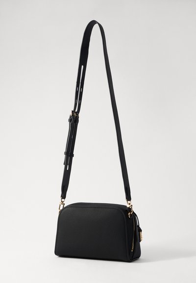 Sac bandoulière noir en matériau texturé, de forme rectangulaire, avec une fermeture éclair, une sangle ajustable et des accents en métal doré.