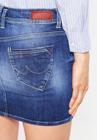 Jeans minikjol i mörkblått med en något bleknad textur, med en bakficka med dekorativ söm och en läderlabel från märket.