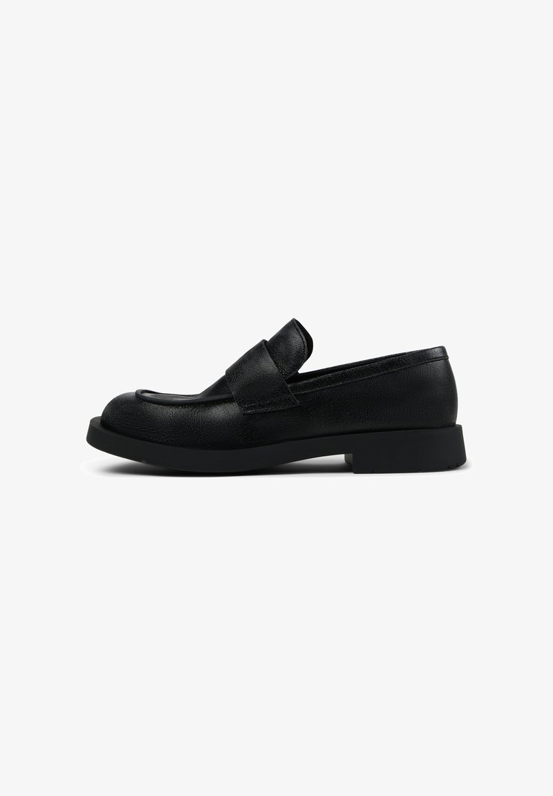 Mocasines de cuero negro con una suela baja y gruesa; presentan una tira ancha en la parte superior y una puntera redondeada; acabado texturizado.