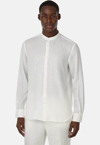 Camicia bianca in lino a maniche lunghe con colletto alla francese, chiusura con bottoni frontali e orlo dritto. Tessuto leggermente trasparente, vestibilità aderente.