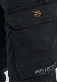 Schwarze Cargo-Hose aus strukturiertem Stoff, mit einer seitlichen Tasche und einem genähten PME Legend-Logo-Tag. Matte Oberfläche mit dezenten Farbvariationen.