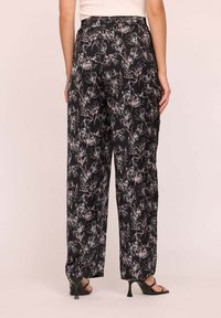 Des pantalons larges à imprimé floral noir avec une taille haute et un tissu léger au toucher doux. Le design inclut des contours subtils de fleurs en blanc.