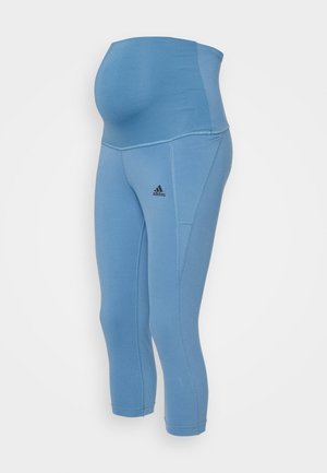 Leggings premaman azzurro chiaro a vita alta con logo Adidas sulla coscia, indossati da un manichino su sfondo bianco.