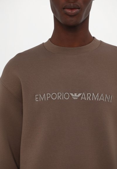 Brown sweatshirt featuring embossed "EMPORIO ARMANI" logo, round neckline, and soft, textured fabric. Classic fit with a minimalistic design.