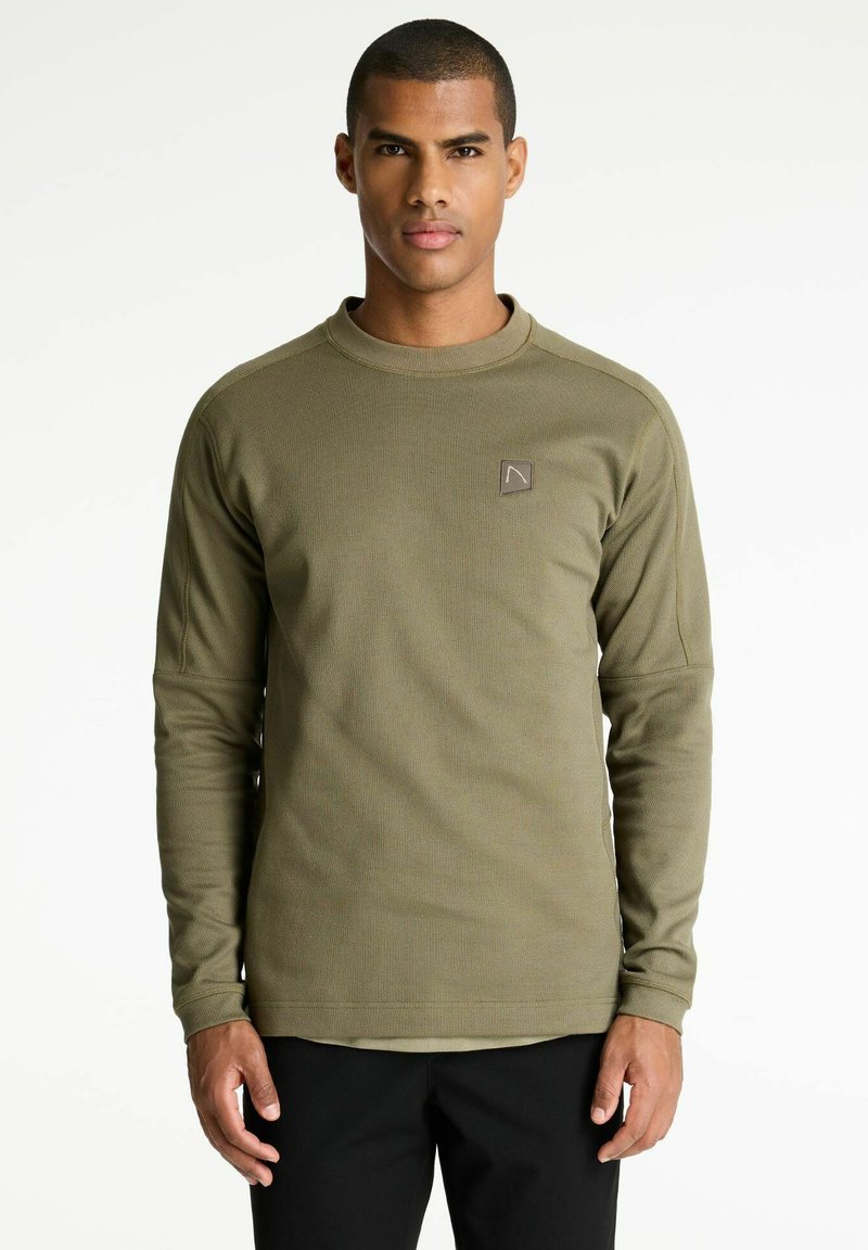 Camisa de manga larga verde oliva hecha de tejido texturizado, con cuello redondo y un pequeño parche con logo en el lado izquierdo del pecho.