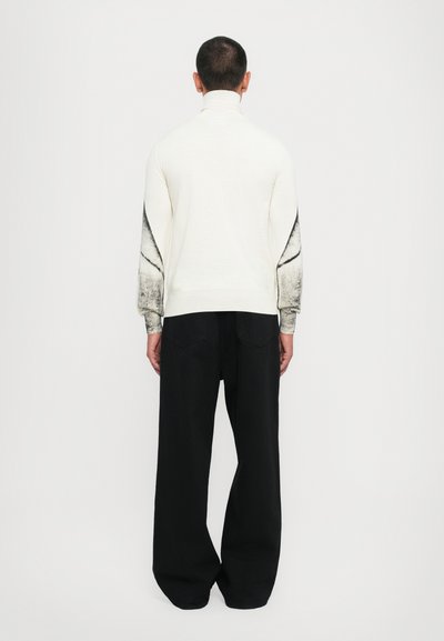 Πλεκτό ζιβάγκο σε κρέμ χρώμα με μαύρες λεπτομέρειες στα μανίκια, φτιαγμένο από μαλακό υλικό. Συνδυάζεται με χαλαρά μαύρα παντελόνια και ελάχιστες λεπτομέρειες.