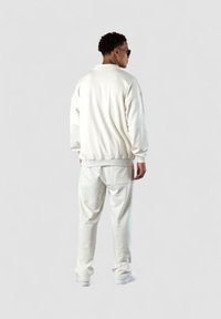 Weißer Sweatshirt mit einem lässigen Schnitt und gerippten Bündchen, kombiniert mit passenden Jogginghosen. Glatte Textur und unauffälliges Design, keine sichtbaren Logos.