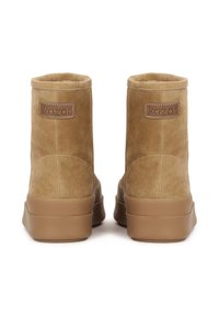 Botoșei până la gleznă din suede bej, cu o textură moale, având o talpă din cauciuc bej. Logo-ul Kazar pe un patch cusut în partea din spate. Formă rotunjită, de înălțime medie.