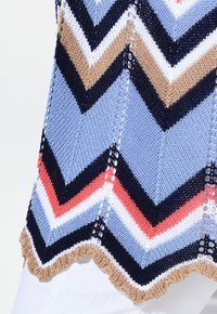 Stickad topp med en chevronmönster i blått, marinblått, kräm och korall, med luggade kanter och öppna detaljer för extra textur.