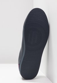 Semelle de chaussure avec motifs circulaires antidérapants et double logo HT au centre, présentée droite sur fond blanc.