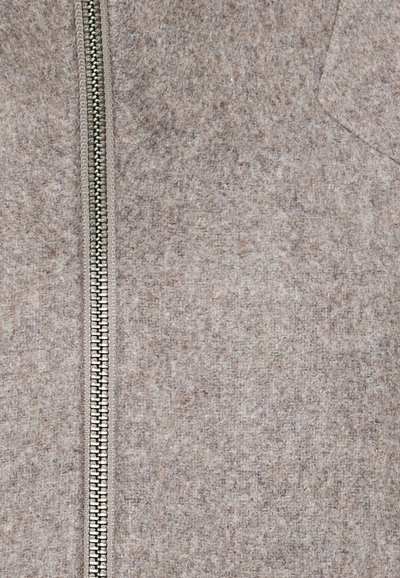 Îmbrăcăminte din material fleece, cu fermoar, de culoare maro deschis, dotată cu un fermoar metalic. Are o textură netedă și un design simplu, fără embellishments suplimentare.