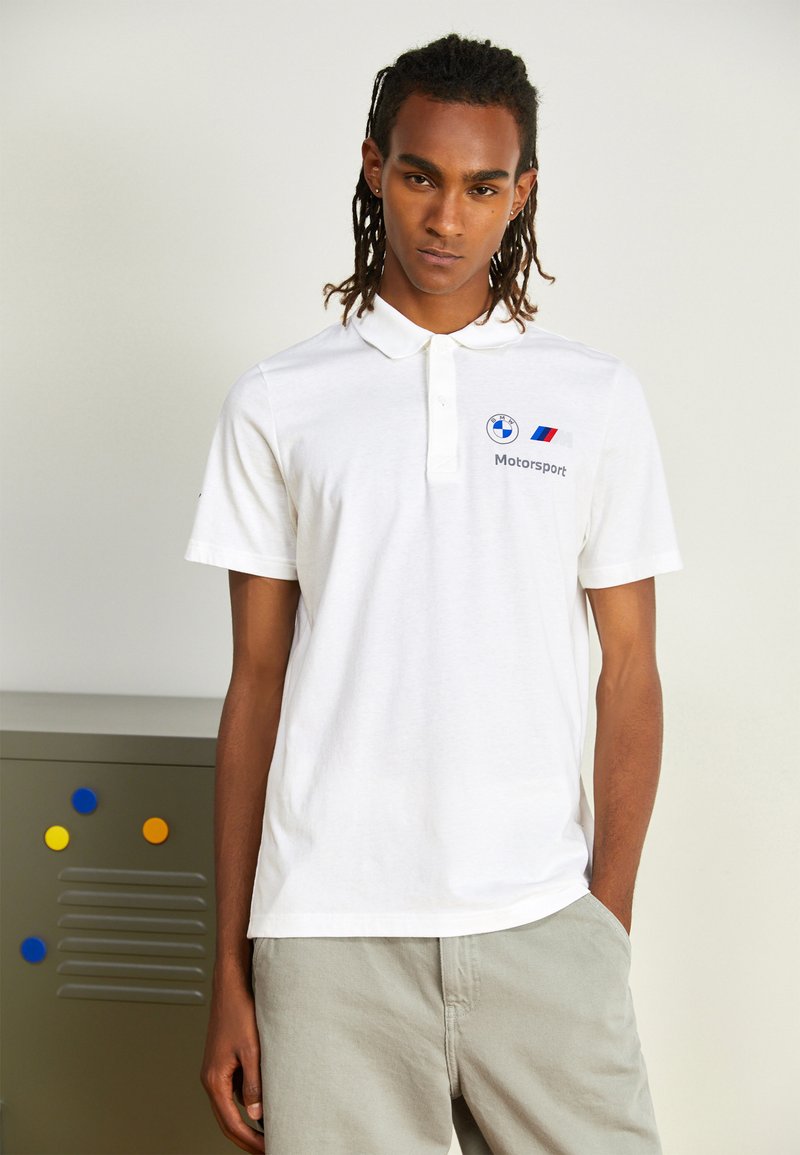Hvid kortærmet polo shirt med krave, med BMW-logo og "Motorsport" tekst. Lavet af bomuld med en glat tekstur.