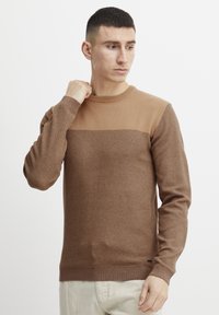 Bruine gebreide trui met een gestructureerd bovenstuk, geribbelde manchetten en een gladde onderlaag. Eenvoudig ontwerp met ronde hals.