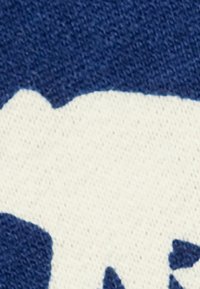 Textil azul marino con un patrón de punto texturizado, que presenta un diseño abstracto blanco en contraste, enfatizando los detalles del material y la forma.