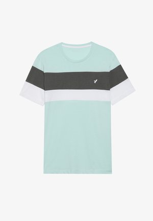 Gaiši zils t-krekls ar horizontālām tumši pelēkām un baltām svītrām, apaļa kakla izgriezums, īsas piedurknes un mazs putna logo uz krūtīm.