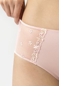 Des culottes rose clair en mesh transparent avec broderie florale d'un côté, tissu lisse et un délicat bord en dentelle festonnée.